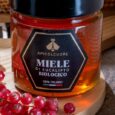 a jar of honey with a black lid and red berries