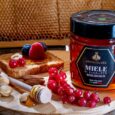 a jar of honey and nuts on a wooden plate