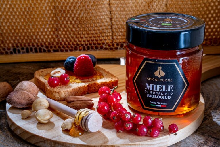 a jar of honey and nuts on a wooden plate